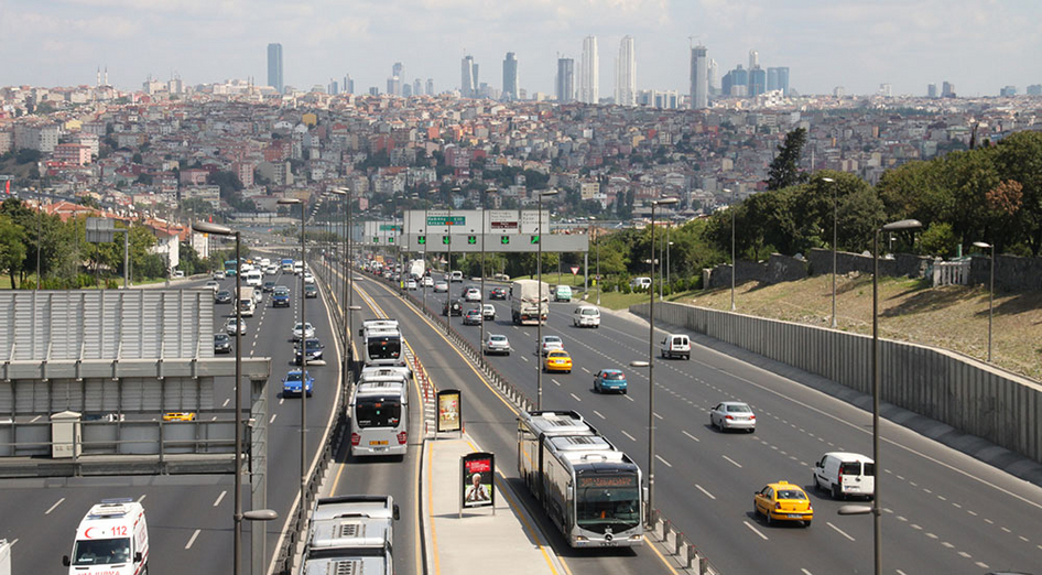 Mehrere befahrene Autobahnspuren mit einigen Bussen in einer Busspur in der Mitte vor der Skyline Istanbuls