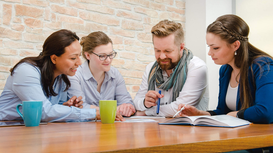 Drei Frauen und ein Mann sitzend bei einer Besprechung am Tisch