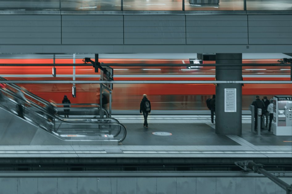 Nahverkehrszug in rot, verwischt, fährt durch Bahnhof