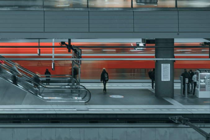 Nahverkehrszug in rot, verwischt, fährt durch Bahnhof