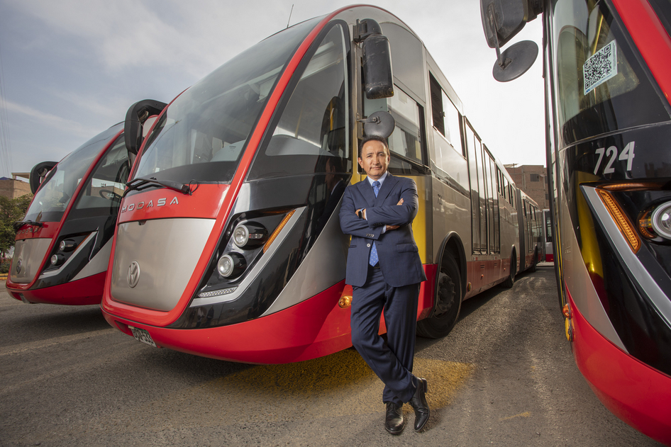 Polo Peréz, CEO von Grupo Polo, lehnt sich an einen roten Grupo Polo Bus, der neben zwei weiteren roten Bussen auf einem Betriebshof steht.