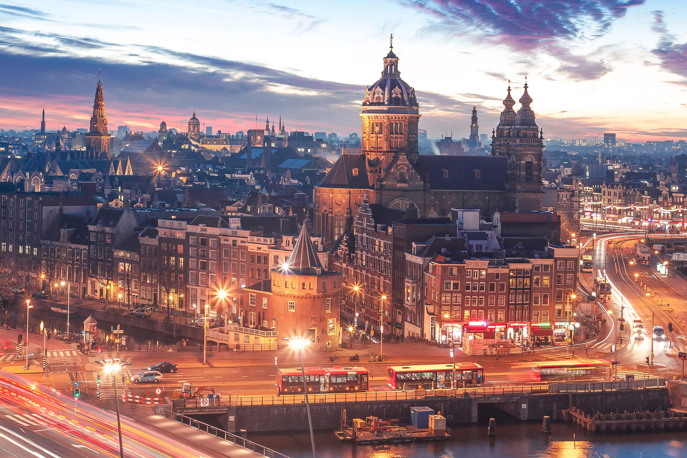 Skyline von Amsterdam in der Dämmerung mit hellen Lichtern